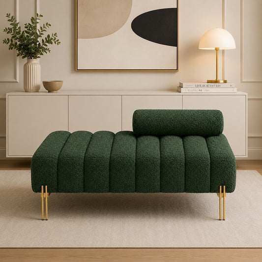 A modern tufted chaise lounge in deep green bouclé fabric with gold metal legs, styled in a minimalist living room setting.